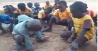 Pupils studying under trees with no furniture to sit on