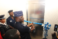 COP Frank Adu Poku (middle) being assisted to cut tape for the commissioning of the elevator