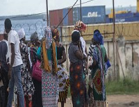 People wait on the outskirts of the seaport of Pemba for the possible arrival of their families