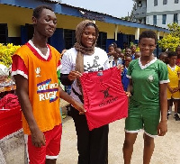 Madam Alemais presents rugby equipment to teams at the selected schools