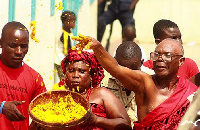 A Ga chief sprinkling 'kpokpoi', the traditional meal at sacred places during the Homowo festival