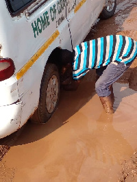 A car trapped in the potholes-mud-ridden road