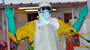 A health worker wearing protective gear is sprayed with disinfectant at the Nongo