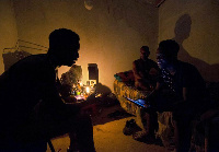 Friends talk by candle light during load shedding in Embo, South Africa