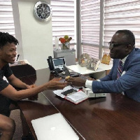 Kwesi Arthur receiving the gift from Bola Ray