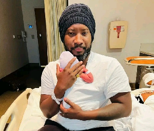 Sonnie Badu holding his newly born baby