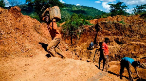 A miner carries a load of ore at Manzou Farm in Mazowe, Zimbabwe on April 5, 2018