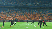 Al Ahly players warm up in an empty stadium as they wait for their opposition to turn up