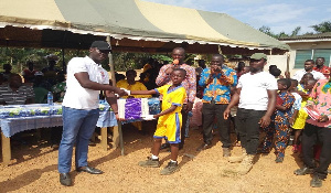 Hon. Charles Kwesi giving out learning materials to a pupil of the school