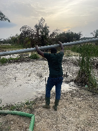 John Dumelo standing by a river at a galamsey site