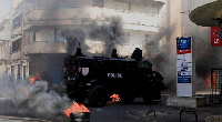 A security forces vehicle drive past burning tyres in capital, Dakar