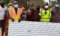 Representatives of the assembly presenting the roofing sheets to affected residents