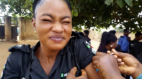 Police officer for Oyo State wey dey squeeze face as dem dey give am AstraZeneca vaccine