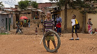 A child plays with a tyre in a slum on the outskirts of Kigali on October 17, 2019 [AFP]