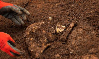 A Burundian worker from the Truth and Reconciliation Commission extracts the skull of an unidentifie