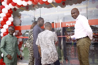 Deputy Trades Minister being assisted to cut the ribbon for the new pharmacy