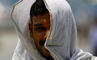 A man covers his face with a cloth to protect himself from the heat