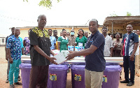 A community member handing the items over to the District Director, Hypolite Yeleduor (R)