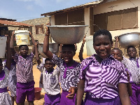 Students of Bright Future International School carrying bowls of water for school use