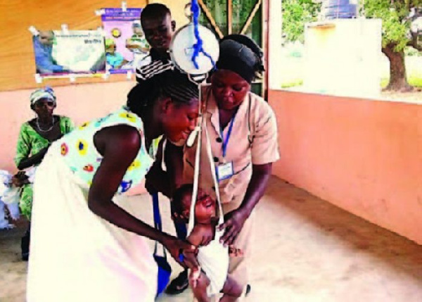 A health official weighing a child