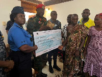 Brigadier General Zibrim Bawa Ayorrogo presenting the cheque. to accident victims