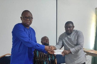 MCE Alfred Amoah (left), hands a cheque to NPP consituency official