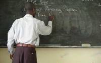 Teacher writing on chalk board.   File photo.