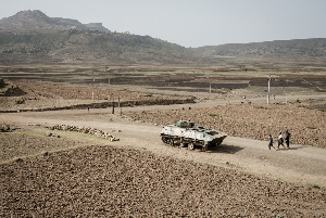 People walk near a tank of alleged Ethiopian army that is abandoned on the road near Dengolat