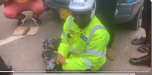 The police officer sitting on the floor begging the protesters