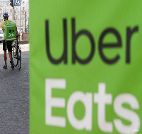 An Uber Eats food delivery courier walks with a bicycle in central Kiev, Ukraine