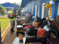 A staff spraying items of students at PRESEC