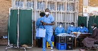 A military health personnel carries an empty medical cooler box at a mobile clinic setup