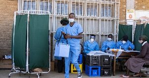 A military health personnel carries an empty medical cooler box at a mobile clinic setup