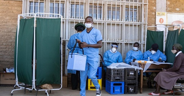 A military health personnel carries an empty medical cooler box at a mobile clinic setup