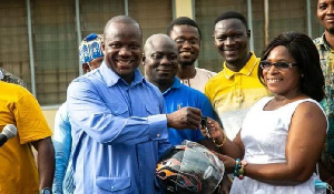 Samuel Abu Jinapor presenting a motorbike key to Madam Gertrude Yentumi