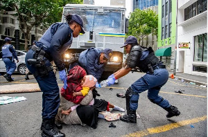 A woman holds onto her baby as South African police remove asylum seekers