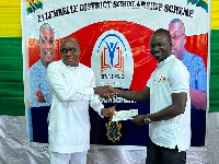 Kwasi Bonzoh presenting a cheque to one of the beneficiaries