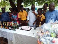 Paul Asare Ansah with students, teachers behind the cake