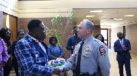 Bishop Adonteng-Boateng in a handshake Captain Michael F. Grinnan (in police uniform)