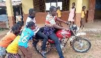 A photo of some students pushing the teacher's motorbike