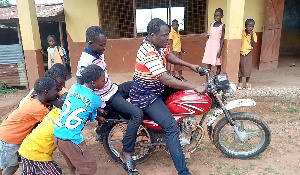 A photo of some students pushing the teacher's motorbike