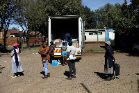 Locals keep social distance as they queue during the distribution of food parcels to vulnerable resi