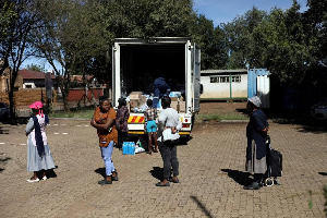 Locals keep social distance as they queue during the distribution of food parcels to vulnerable resi