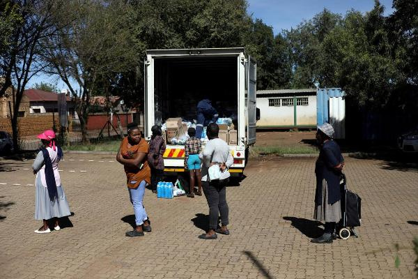 Locals keep social distance as they queue during the distribution of food parcels to vulnerable resi