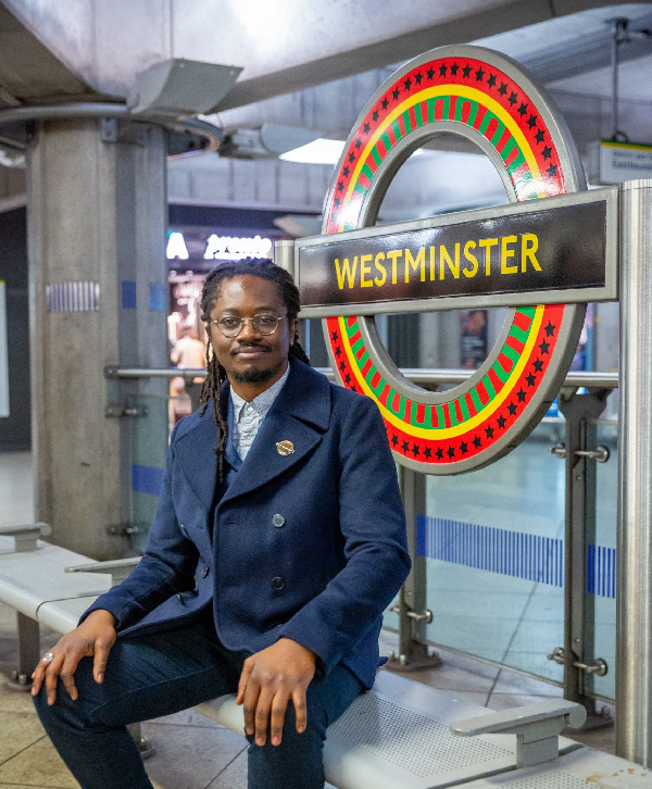 Larry Achiampong poses in front of his installation at the Westminster Station