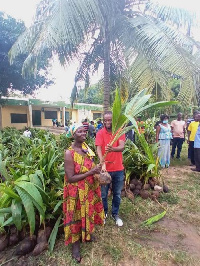 Mr Isaac Kwadwo Buabeng, the Nsawam-Adoagyiri MCE presents a seedling to a farmer