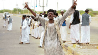 A protester flashes victory signs following the arrival in Port Sudan of a delegation