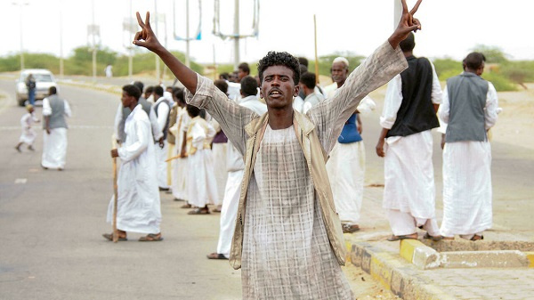 A protester flashes victory signs following the arrival in Port Sudan of a delegation