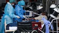 Professional healthcare workers wearing personal protective equipment attending to a patient