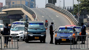 A police officer controls a car at a roadblock to restrict inter-city movement